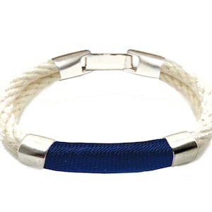 May include: A white rope bracelet with a blue fabric band and silver metal accents.