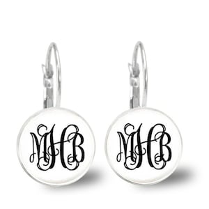 May include: A pair of silver hoop earrings with a white round charm featuring a black monogram "MHB" in a script font.