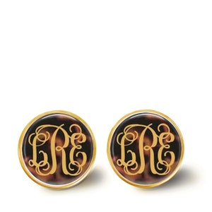 May include: A pair of gold-toned stud earrings with a tortoiseshell pattern and the monogram "LRE" in gold lettering.