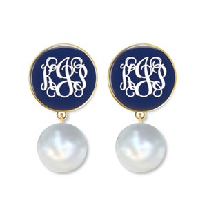 May include: A pair of gold-tone drop earrings with a navy blue round disc featuring a white monogram and a white pearl dangling below.