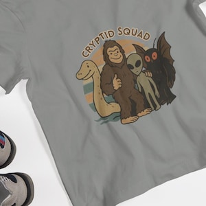 Cryptid Squad Jugend Kurzarm-T-Shirt, Jungen, Mädchen, Cryptid, Natur, Bigfoot, Mottenmann, Loch Ness Monster, Aliens, UFO, Kreaturen