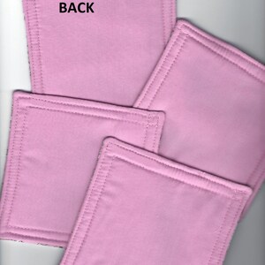 May include: Four pink fabric squares with a stitched border. The back of one square has the word "BACK" written on it.