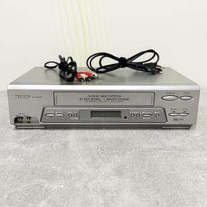 May include: A silver Sharp VC-AA550 4-head multi-system VCR with a central cassette compartment, digital display, and various control buttons. The front panel features the text 4-HEAD MULTI SYSTEM EP RECORDING / 1 MINUTE REWIND. Includes black power and RCA cables.