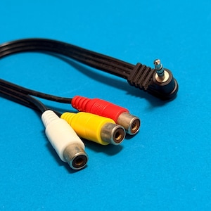 May include: A black AV cable with three RCA connectors in white, yellow, and red, and a 3.5mm jack. The cable is on a blue surface.