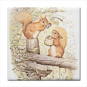 May include: A square decorative tile featuring a watercolor illustration of two brown squirrels. One squirrel sits on a tree stump holding a small object, while the other stands on a fallen log holding a light-colored, textured, cylindrical item.