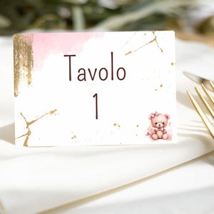 Puede incluir: Una tarjeta de mesa blanca con detalles en acuarela rosa y detalles dorados. La tarjeta dice "Tavolo 1" en texto marrón y presenta una ilustración de oso de peluche en acuarela. Ideal para un evento.