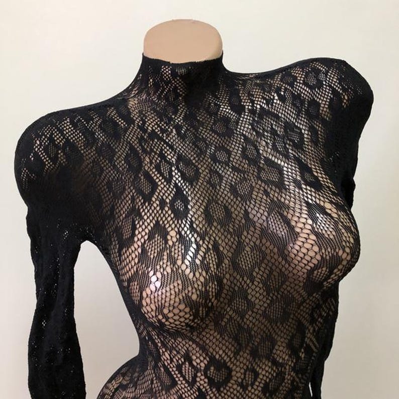 Puede incluir: Body negro de manga larga con cuello alto. La tela transparente presenta un patr&oacute;n texturizado en forma de diamante. La prenda se exhibe en un maniqu&iacute;.