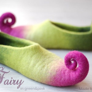 Könnte beinhalten: Ein Paar grüne und rosa Filzpantoffeln mit einer gekräuselten rosa Zehe. Die Pantoffeln heißen "Fairy" und werden von Zavesfelt hergestellt.