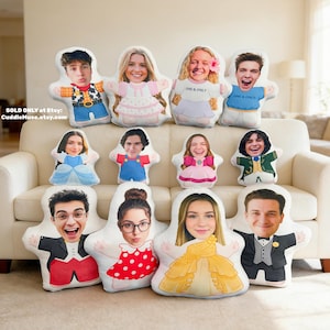 May include: A collection of personalized plush pillows with faces printed on them. The pillows are shaped like people with various outfits, including a princess dress, a tuxedo, and a Woody costume. The pillows are arranged on a white couch.