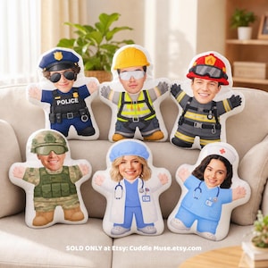 May include: Six custom-shaped plush pillows featuring printed illustrations of people in various professional uniforms, including a police officer, construction worker, firefighter, soldier, doctor, and nurse, with the text Cuddle Muse.etsy.com.