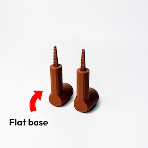 May include: Two brown bottle stoppers with a flat base. Each has a cylindrical body and a textured, conical top. The text "Flat base" is below the stoppers with a red arrow pointing to them.
