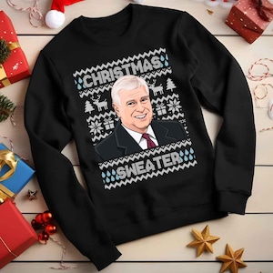 May include: Black Christmas sweater featuring a portrait of a smiling man in a suit. The sweater has the words "CHRISTMAS SWEATER" in a white, pixelated font, along with snowflakes, reindeer, and gift box designs.