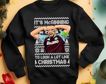 May include: Black sweatshirt featuring a cartoon image of a man in a maroon and blue jersey. The text on the sweatshirt says "IT'S McGINNING TO LOOK A LOT LIKE CHRISTMAS."