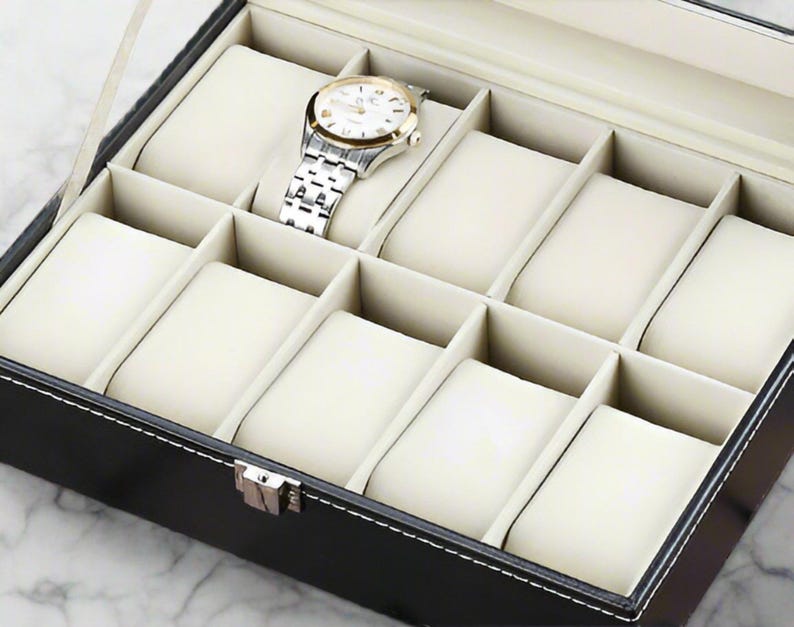May include: Black leather watch box with a clear lid and 10 compartments lined with white velvet. The box is designed to hold and display watches.