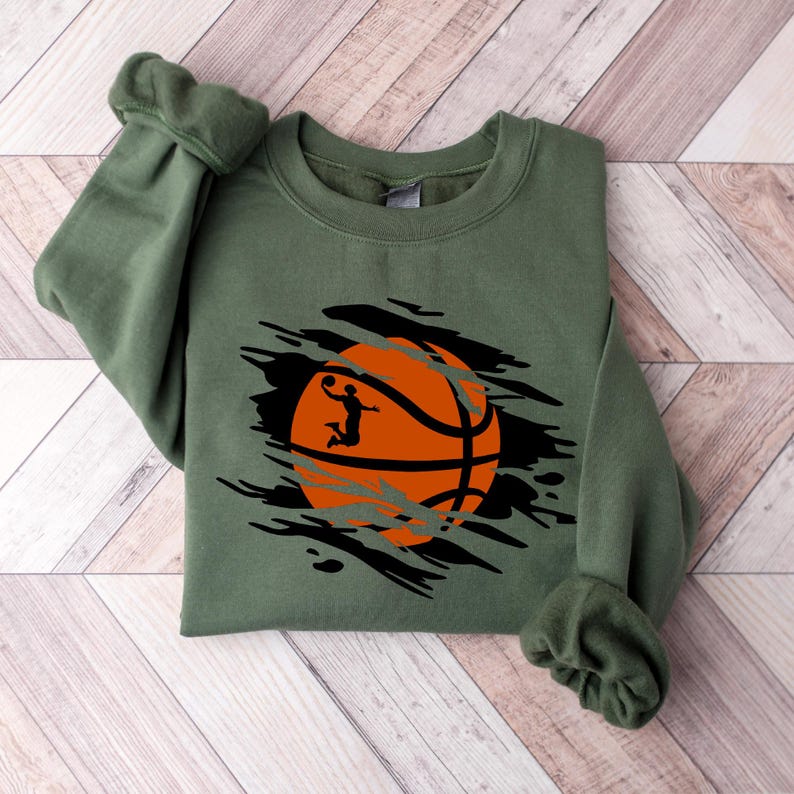 May include: A green sweatshirt with a distressed graphic of an orange basketball with a silhouette of a player dunking.