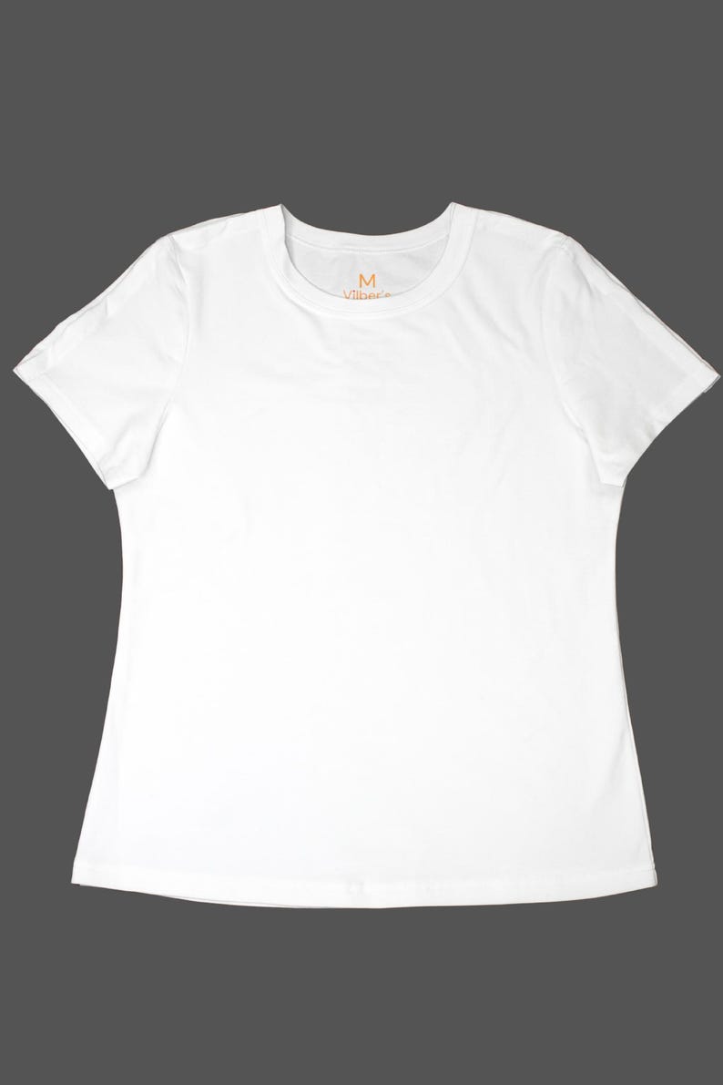 K&ouml;nnte beinhalten: Ein schlichtes wei&szlig;es T-Shirt mit Rundhalsausschnitt und kurzen &Auml;rmeln. Das Shirt hat ein schlichtes, klassisches Design und ist aus einem weichen, wahrscheinlich atmungsaktiven Stoff gefertigt. Der Markenname "Vibes" ist in Orange auf der Brust aufgedruckt.