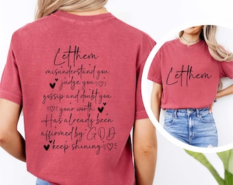 May include: A crimson short-sleeve t-shirt featuring black text on the back that reads: Let them misunderstand you, judge you, gossip and doubt you. Your worth has already been affirmed by GOD. Keep shining. The front features the word Let them.