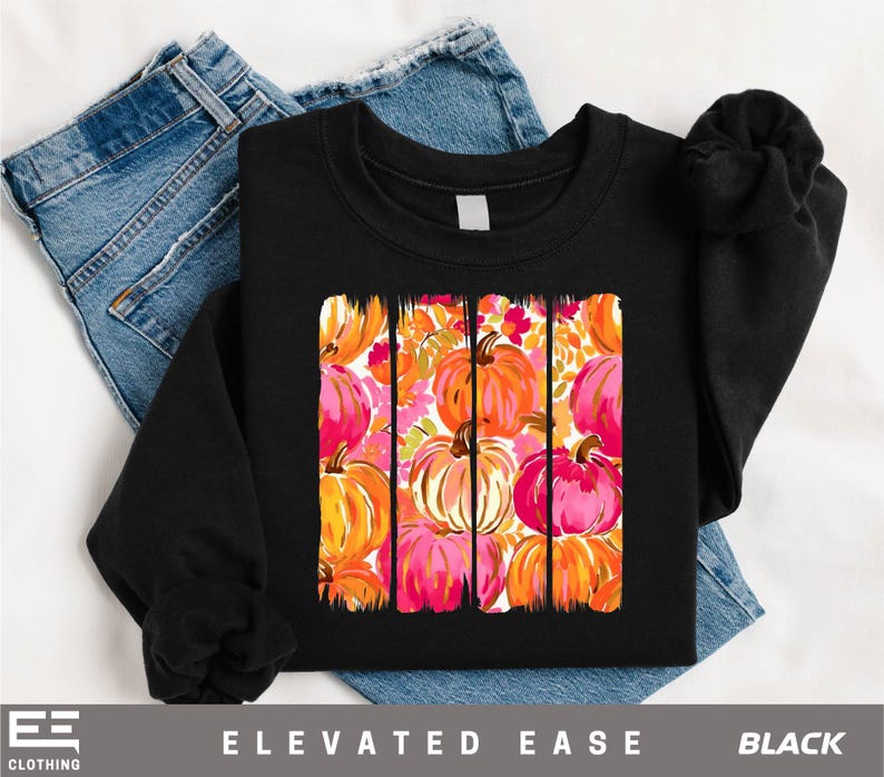 A black t-shirt with a vibrant graphic design of colorful pumpkins on it, along with a pair of blue jeans.