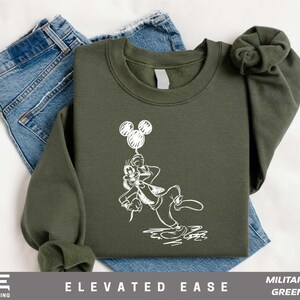 a green sweatshirt with a mickey mouse graphic on it