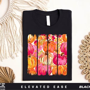 a black t-shirt with a vibrant graphic design of colorful pumpkins and flowers printed on it.