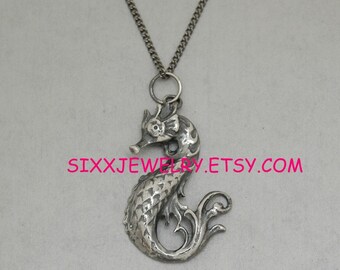 May include: A silver seahorse pendant necklace with a detailed design. The pendant is attached to a silver chain.
