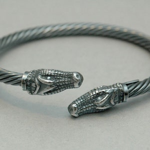 May include: A silver bracelet with a twisted cable design and alligator head ends.