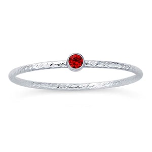 May include: A silver ring with a textured band and a single red gemstone.