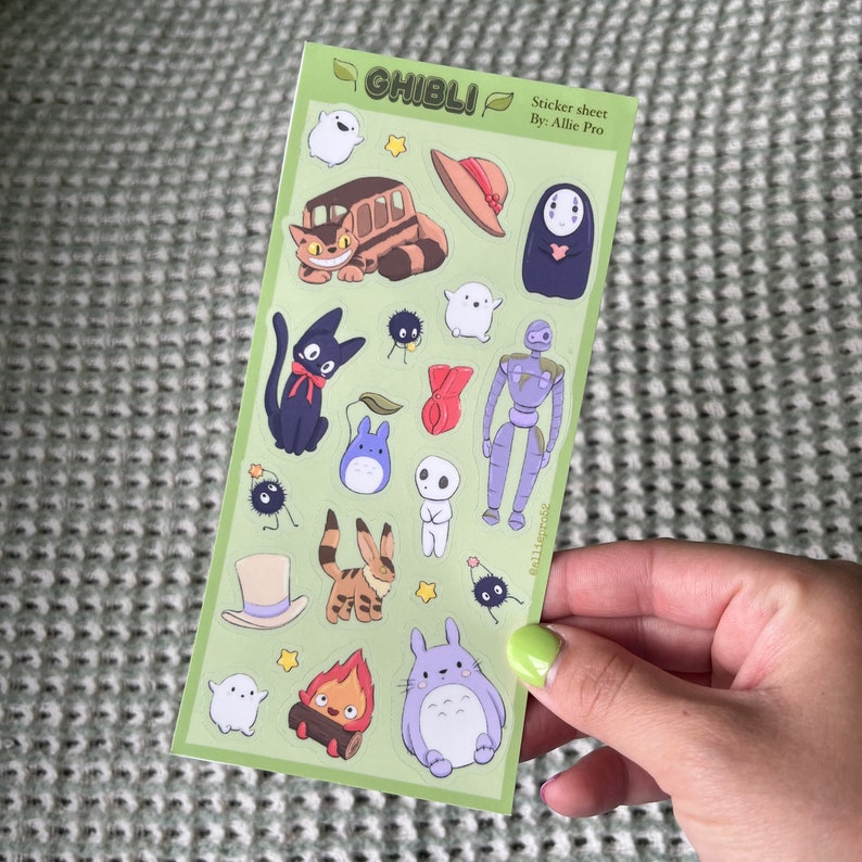 May include: A sticker sheet featuring various characters from Studio Ghibli films. The stickers include the Catbus, Totoro, No-Face, and other recognizable figures. The sheet has a light green background with the word "GHIBLI" at the top.