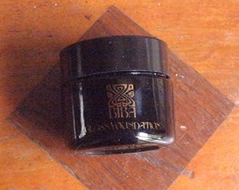 Fondotinta lucido BIBA originale vintage dei primi anni '70, in vetro rotondo, nero lucido. Contenuto originale: 1 colore: giallo. Peso: 20 g. Un solo proprietario. Eccellente.