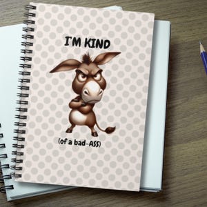 May include: Spiral-bound notebook with a cover featuring a cartoon donkey with an angry expression. The text "I'M KIND (of a bad-ASS)" is printed on the cover. The background has a pattern of light gray polka dots.
