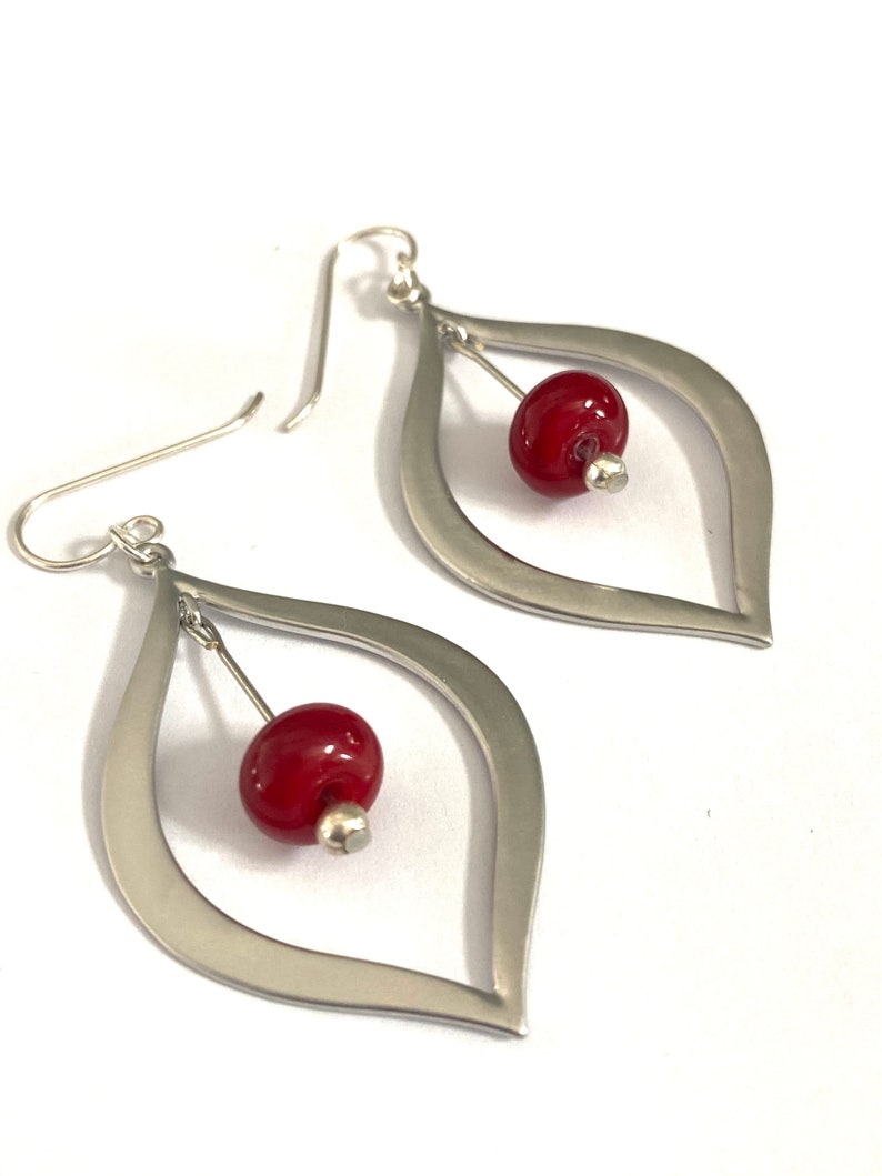 Red glass beaded silver teardrop earrings featuring sterling silver ear wire. These gorgeous, classic in style earrings feature glass beads that I made using a torch and kiln. The length of these red beaded dangle earrings is two inches.