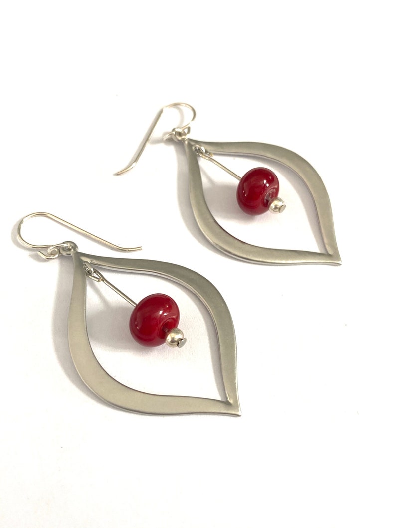 Stunning silver teardrop earrings with gorgeous red lampwork bead earrings floating in the center. These beads are made by hand using a torch and kiln.