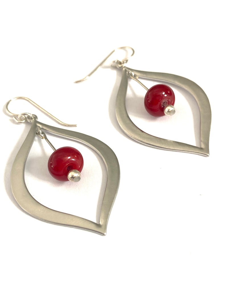 Two inch dangle earrings feature silver metal and red glass beads.