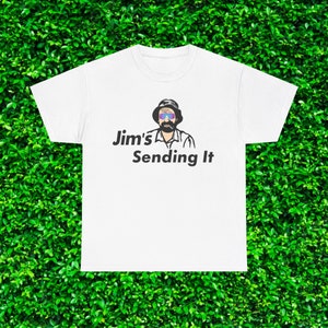 May include: White t-shirt featuring a cartoon illustration of a man in sunglasses and a hat. The text "Jim's Sending It" is printed below the graphic in black. The shirt is set against a green leafy backdrop.