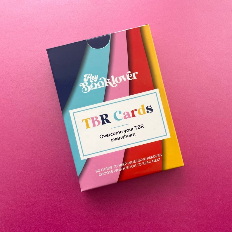 May include: A deck of TBR Cards with a colorful striped design. The text on the front reads "Hey Booklover TBR Cards Overcome your TBR overwhelm 30 cards to help indecisive readers choose which book to read next."