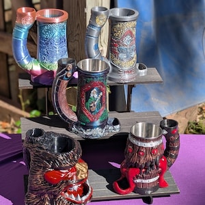 May include: A collection of decorative beer steins with unique designs. The steins feature various colors and themes, including fantasy and nature-inspired motifs. Some steins have intricate handles and detailed artwork, showcasing a range of styles.