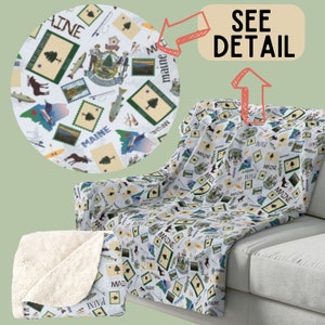 Peut inclure: Une couverture en polaire blanche avec un motif répété de diverses images liées au Maine, notamment le drapeau de l'État, un pin, un élan, un poisson et les mots "Maine" et "Viva Maine".