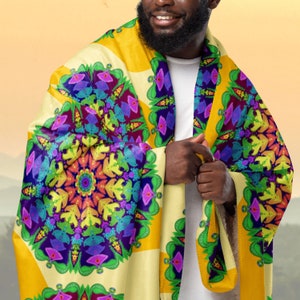 May include: A yellow, white, and green fleece blanket with a colorful mandala pattern. The blanket is folded and draped over a person's shoulders.