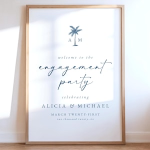 May include: A framed sign for an engagement party. The design includes a palm tree graphic and the words "welcome to the engagement party." The names "Alicia & Michael" and the date "March twenty-first" are also displayed in a stylish font.