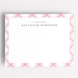 Puede incluir: Una tarjeta de papelería blanca con un borde de cuadros rosas. El texto "a note from, SAVANNAH ROBINSON" está centrado en la parte superior. La tarjeta es rectangular y está sobre un fondo blanco.