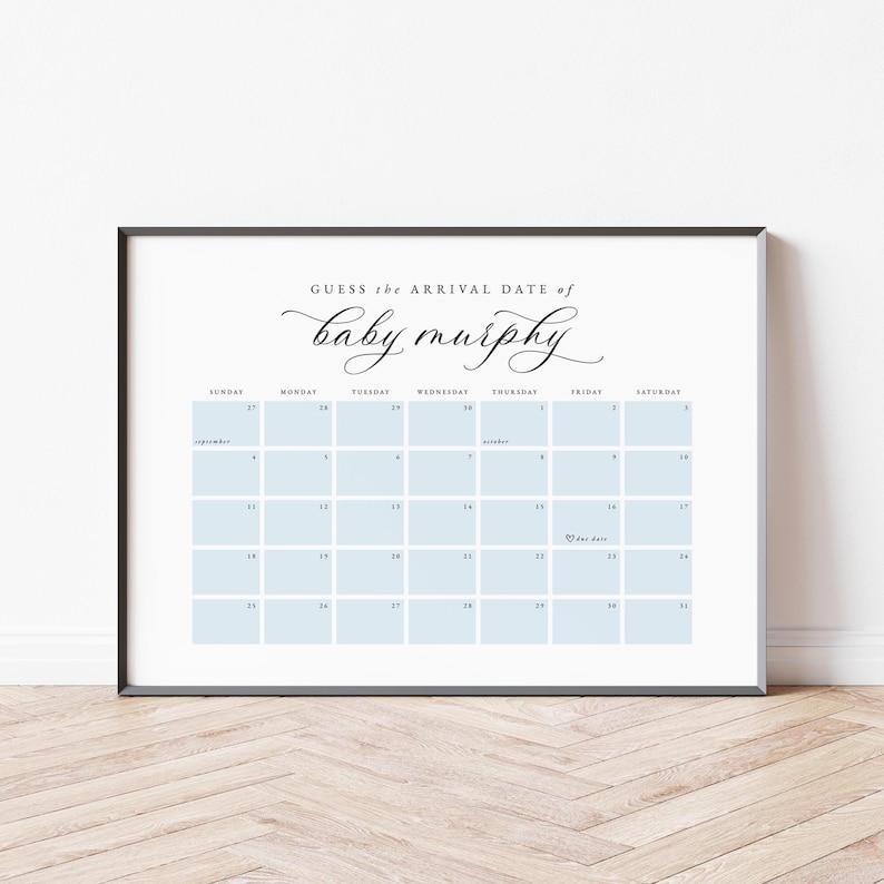 May include: A framed calendar print with a white background and a black border. The calendar has light blue squares for each day and the text "Guess the Arrival Date of baby murphy" in elegant script. The calendar is a baby shower game.