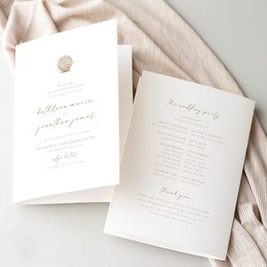 May include: A white wedding program with gold lettering. The program includes the names of the bride and groom, Kathleen Marie and Jonathan James, the wedding date, and the wedding party. The program also includes a thank you message to the guests.