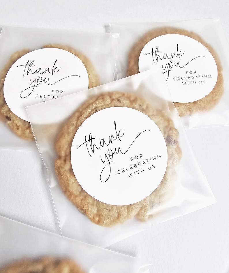May include: Three clear plastic bags containing cookies. Each bag has a round white sticker with black text that reads "Thank you" and "For Celebrating With Us".