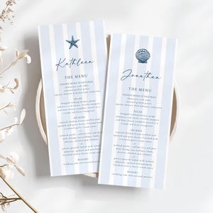 Könnte beinhalten: Zwei elegante Menükarten mit blau-weiß gestreiften Hintergründen. Die Karten zeigen die Namen "Kathleen" und "Jonathan" in Schreibschrift sowie Menüdetails. Ein Seestern und eine Muschel zieren die Oberseite jeder Karte.
