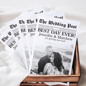 May include: Wedding announcement cards styled as newspaper front pages. The headline "BEST DAY EVER!" is displayed, with the names Jennifer & Matthew, and the date August 1, 2026. A black and white photograph of the couple is included.