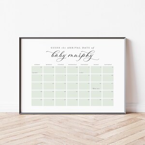 May include: A framed calendar print with the text "Guess the arrival date of baby murphy" in elegant script. The calendar grid features pale green squares and dates for September. A heart icon marks a date.