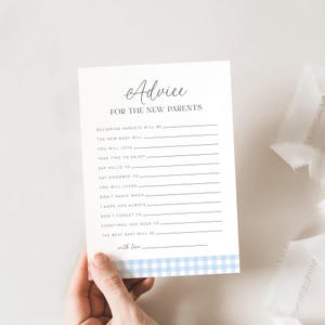 Op de afbeelding: Een witte advieskaart voor nieuwe ouders, vastgehouden door een hand. De kaart bevat het woord "Advice" in elegant schrift, gevolgd door vragen om in te vullen. Een blauw en wit geruit patroon versiert de onderste rand.