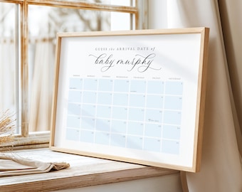 May include: A framed calendar print with the text "Guess the Arrival Date of baby murphy" in elegant script. The calendar grid features light blue squares for each day. The frame is made of light-colored wood.