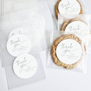 May include: Clear cellophane bags filled with cookies and round white stickers that say "Thank you for celebrating with us".