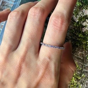 May include: A silver band ring with a row of small purple gemstones.